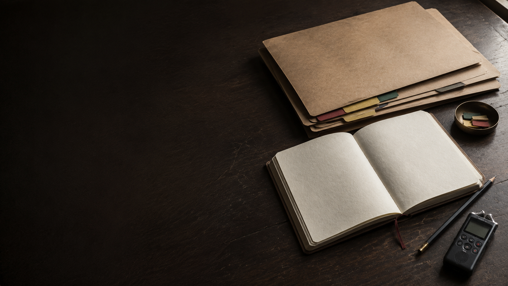 Open notebook, anonymised case files, pencil and audio recorder arranged on a documentation desk.